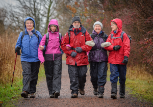 five walkers in the rain walking with arms linked